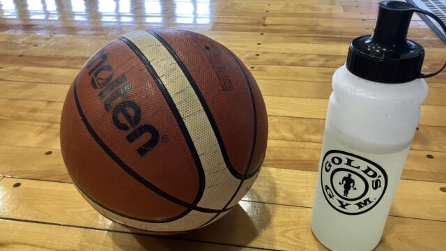 体育館のフロアに置いた、バスケットボールとドリンクの画像